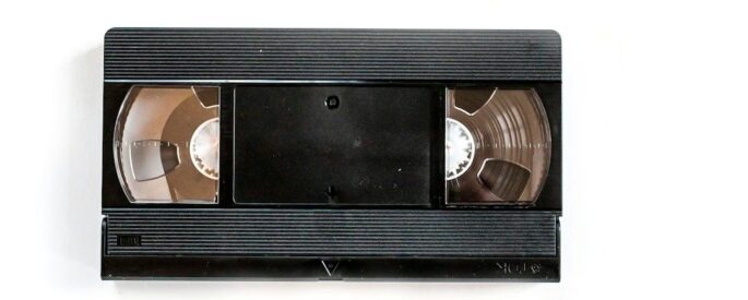 Svart VHS-kassett med två synliga bandspolar mot vit bakgrund